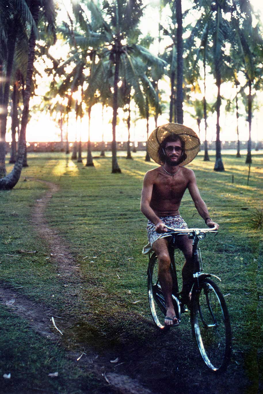 Peter riding a bike through the coconut trees on the beachfront in Kuta in the 70s
